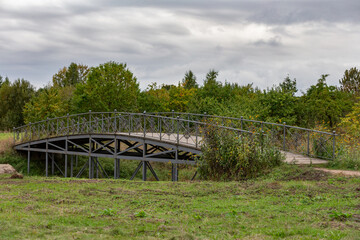 Fototapeta na wymiar Wooden bridge in the Leningrad region with a railing in autumn weather overlooking the distance.