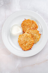 Potato pancakes fried in a frying pan and laid out on a white plate. Classic hash browns from potatoes, top view