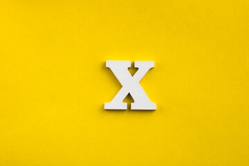 Alphabet letter X - White wood letter on yellow colored background