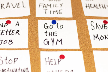 Close up of white post-it notes with new year's resolutions on a cork board. Text: Go to the gym