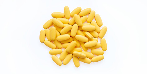 Close-up texture of yellow multivitamin tablets on white background. Healthy lifestyle concept