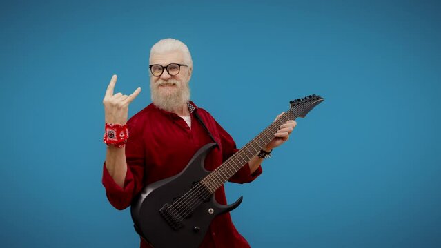 Man in his 60s showing heavy metal and hard rock horns hand gesture, guitarist