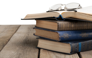 Stack old books with reading glasses on desk