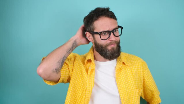 A thoughtful confused guy is trying to find a way out of a difficult situation, he scratches his head from confusion and is visibly nervous, but is forced to admit the hopelessness of the situation.