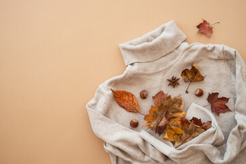 Autumn flat lay. Warm sweater with fall leaves at color backgroumd.