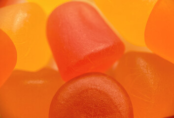 Close-up texture of orange and yellow multivitamin gummies on white background. Healthy lifestyle concept