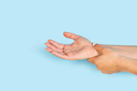 Mano de mujer con dolor de muñeca sobre un fondo celeste pastel liso y aislado. Visat de frente y de cerca. Copy space. Concepto: padecer el síndrome del túnel carpiano