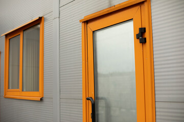 Orange door to building. Entrance to office. Door with glass.