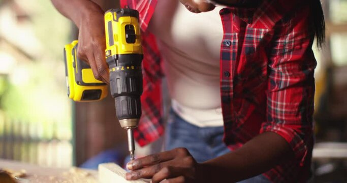 Young woman using a screwdriver on a piece of wood while working in a workshop