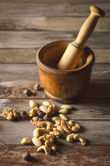 Différentes variétés de fruits à coques et mortier et pilon en bois en arrière-plan