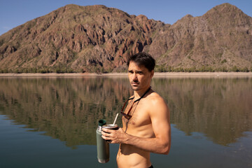 Portrait of a shirtless young caucasian man drinking traditional yerba mate herb infusion drink,...