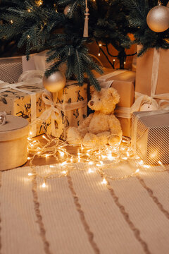 Vertical image of cozy flat apartment room green Christmas Tree gifts presents garlands, candles decorated toys balls interior New Year beautiful living room in the evening, lights glowing bokeh
