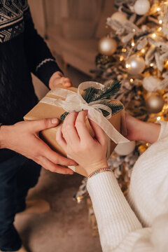 Vertical image lovely young romantic couple sitting open gifts presents garlands home cosy interior atmosphere New Year Christmas tree decorations holiday party celebrating winter evening 
