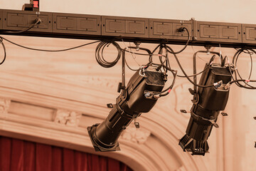 Closeup photo of new large theater spot lights hung within an older theatre or auditorium.
