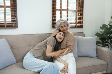 Portrait loving adult asian people daughter and senior mature mom hugging on couch.