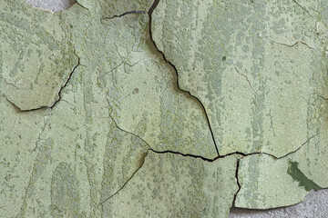 Peeling paint on the wall. Old concrete wall with cracked flaking paint. Weathered rough painted surface with patterns of cracks and peeling. High resolution texture for background and design. Closeup