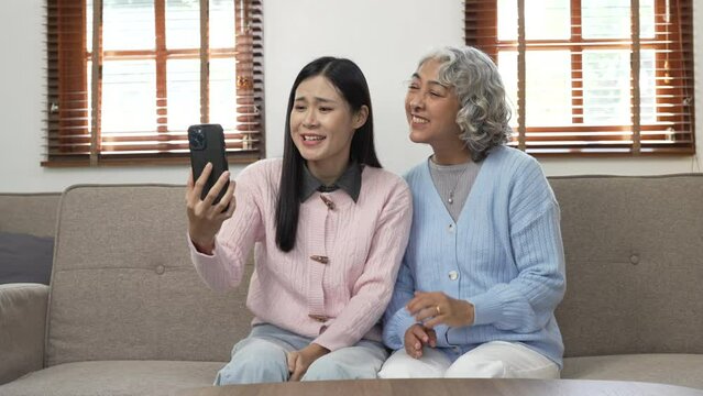 Asia mature woman mother with doughter sitting on sofa.