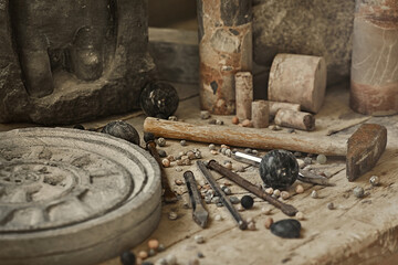 background with various tools for working with stone. Stone sculptures in the background in the workshop. hand made