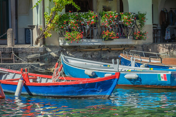 Idyllic Limone sul Garda pier with colorful boats at summer, Italian alps