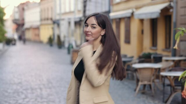 Female flirting, woman walking, confident businesswoman. Stylish young woman with long hair walking in city, spinning, turning, smiling and flirting outdoors, back view of woman walking outdoors.