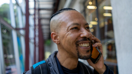 black man talks on cellphone and listens to music on an afternoon in the city
