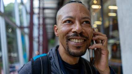 black man talks on cellphone and listens to music on an afternoon in the city