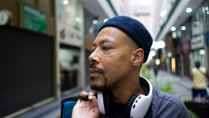 black man talks on cellphone and listens to music on an afternoon in the city