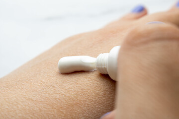 Hands of a white woman applying cream to dry skin. Mention of skin care, hydration and daily care for people concerned with health, beauty and well-being.