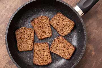 Rye read slices in frying pan close-up. Pieces of fried, dried bread, toast