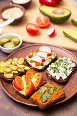 Vegan, vegetarian sandwich, toast with different various vegetables and greens on bread on plate on kitchen. Healthy fast food, snack 