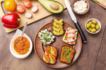 Vegan, vegetarian sandwich, toast with different various vegetables and greens on bread on plate on kitchen. Healthy fast food, snack 