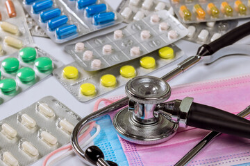 This is doctors office desk with stethoscope and of blister packs containing many different types medicine pills