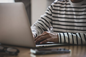 Close up image of side view of male hands typing on laptop keyboard.