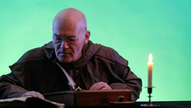 Video of old monk takes a manuscript out of the document box, signs it and puts it back. Green screen chroma key background.