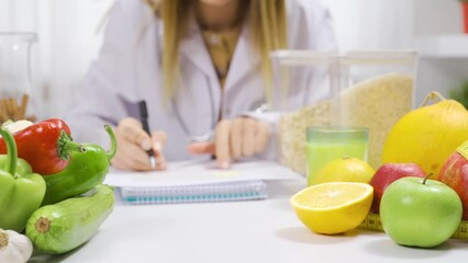 Nutritionist woman emphasizing wellness and nutrition.
Working at a table full of fruits and vegetables, a dietitian prepares a healthy diet program.
