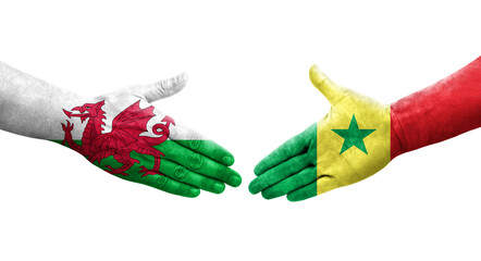 Handshake between Senegal and Wales flags painted on hands, isolated transparent image.