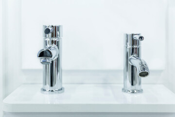 Water faucets on the sink in a stylish white interior. Exhibition of samples. Front view. Close-up....