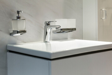 Faucet for water over a white sink. Close-up. Selective focus. Stylish interior.