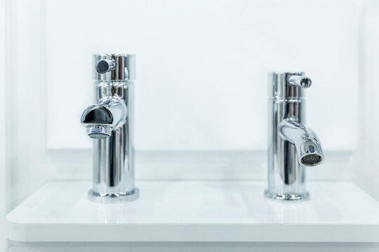 Water faucets on the sink in a stylish white interior. Exhibition of samples. Front view. Close-up. Selective focus.