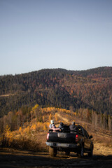 Car truck is going down on offroad with people in mountains during autumn day