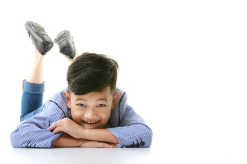 A 10-year-old Asian boy in a casual jacket is lying on the floor and smiling happily in a good mood looking at the camera. Positive concepts for children and young men's lifestyles. - 545336156