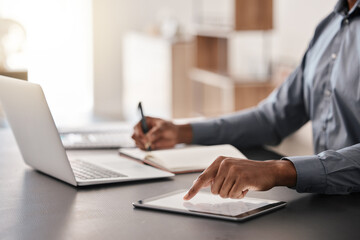 Tablet, laptop and hands of businessman writing notes in a notebook doing corporate research in modern office. Technology, professional and closeup of manager working on online project in workplace.