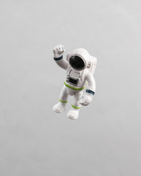 Toy astronaut model flying in antigravity on gray background