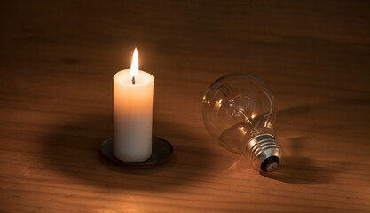 lit candle and lamp on the wooden table.  Lack of electricity. 