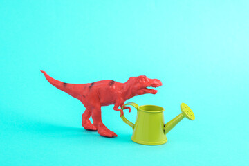 Toy red dinosaur tyrannosaurus rex with watering can on a turquoise background. Minimalism creative...