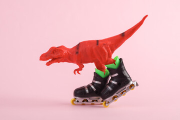 Toy red dinosaur tyrannosaurus rex with roller skates on pink background. Minimalism creative layout