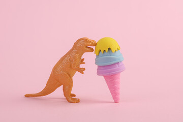 Toy dinosaur tyrannosaurus rex with ice cream on pink background. Minimalism creative layout