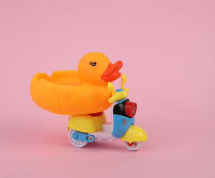 Rubber duck ride on scooter, pink background.