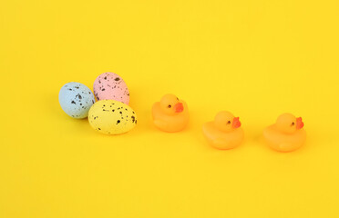 Fototapeta na wymiar Rubber little ducklings with easter eggs on a yellow background