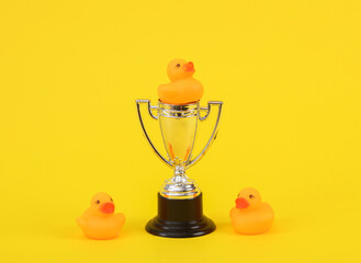 Rubber little ducklings with winner cup on a yellow background